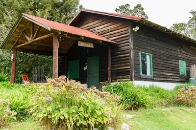 a log cabin with green doors and a red roof at Villa Pajon Eco Lodge in Constanza