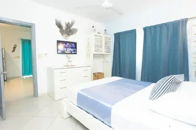 a white bedroom with two beds and a tv at Las Terrenas, La Fenice, Playa Popy in Las Terrenas