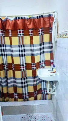 a bathroom with a plaid shower curtain and a sink at Apartahotel carla in Boca Chica