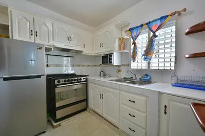 a kitchen with white cabinets and a stainless steel refrigerator at Villa Alégria in Santa Bárbara de Samaná