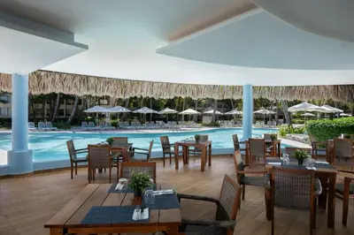 a restaurant with a pool and tables and chairs at Impressive Punta Cana - All Inclusive in Punta Cana