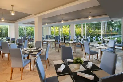 a restaurant with tables and chairs and windows at Impressive Premium Punta Cana - All Inclusive in Punta Cana