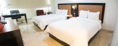 a hotel room with two beds and a desk at Radisson Hotel Santo Domingo in Santo Domingo