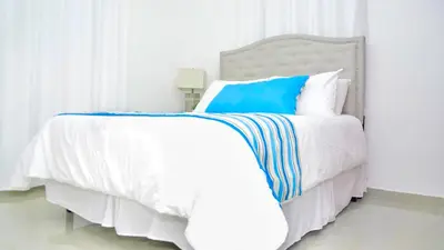 a white bed with blue and white sheets and pillows at Dolce Villas at Harmony 2 in Santiago de los Caballeros