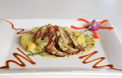 a plate of food with meat and mashed potatoes at Puerto Blanco Marina & Hotel in Puerto de Luperon