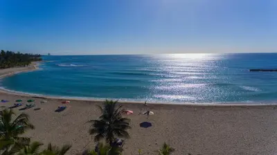 a beach with a group of people and the ocean at Aparta Hotel Caribe Paraiso in Juan Dolio