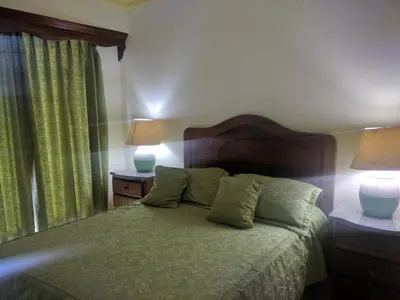 a bedroom with a green bed with two lamps at Aparta Hotel Caribe Paraiso in Juan Dolio