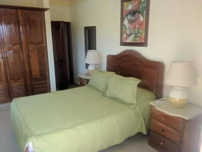 a bedroom with a bed with green sheets and two lamps at Aparta Hotel Caribe Paraiso in Juan Dolio