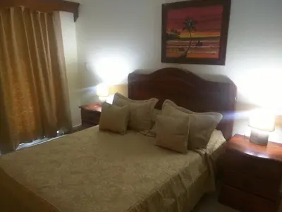 a bedroom with a bed with two lamps and two tables at Aparta Hotel Caribe Paraiso in Juan Dolio