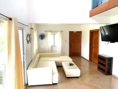 a living room with a couch and a tv at Villa Vista azul Sosua in Sosúa