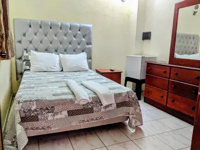 a bedroom with a bed and a dresser and a mirror at Hotel Aluge in Santo Domingo
