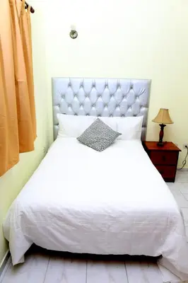 a bedroom with a white bed with a silver headboard at Hotel Aluge in Santo Domingo