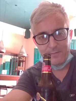 a man wearing glasses is holding a beer bottle at Hotel Aluge in Santo Domingo