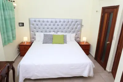 a bedroom with a large white bed with two night stands at Hotel Aluge in Santo Domingo