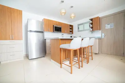 a kitchen with a stainless steel refrigerator and stools at Presidential Suites Cabarete - Room Only in Cabarete