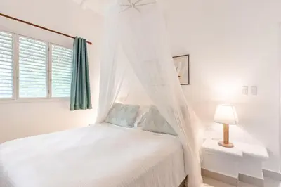a white bedroom with a bed with a canopy at Caribbean Beach Villa Playa Bonita Las Terrenas in Las Terrenas