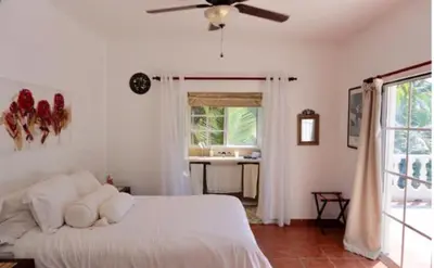 a bedroom with a white bed with a ceiling fan at Baoba Breeze Bed & Breakfast- beachfront paradise in Cabrera