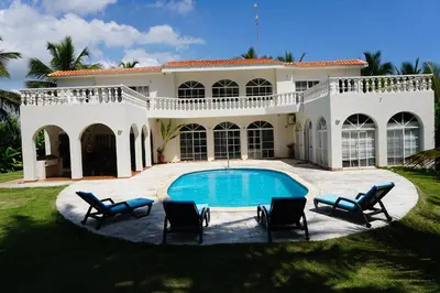 a large white house with a swimming pool and chairs at Baoba Breeze Bed & Breakfast- beachfront paradise in Cabrera