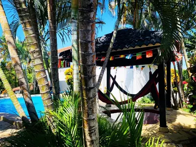 a resort with a hammock next to a pool at HappiCasaRD & Holistic House in Sosúa