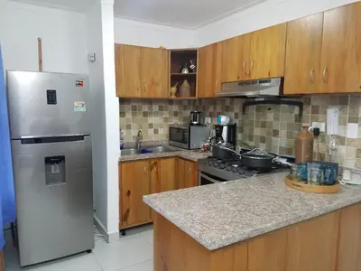 a kitchen with wooden cabinets and a stainless steel refrigerator at Ave. Duarte k3/12, Residencial Palma Real, Santiago, RD in Arenoso