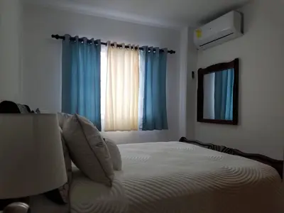 a bedroom with a bed and a window with blue curtains at Ave. Duarte k3/12, Residencial Palma Real, Santiago, RD in Arenoso