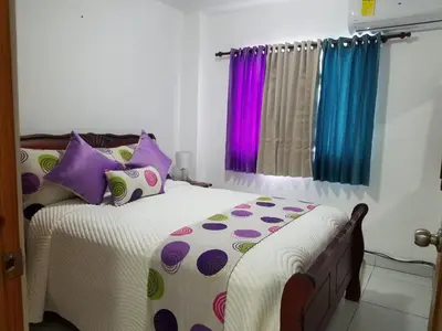 a bedroom with a bed with colorful pillows at Ave. Duarte k3/12, Residencial Palma Real, Santiago, RD in Arenoso