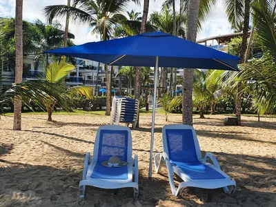 two blue chairs and an umbrella on a beach at Palmeraie Terrenas Beach Apartment in Las Terrenas