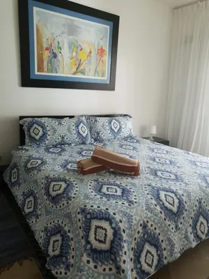 a bed with a blue and white comforter with a purse on it at Palmeraie Terrenas Beach Apartment in Las Terrenas