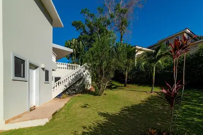 a white house with a yard with grass and trees at 883 Residencial Casa Linda in Sosúa