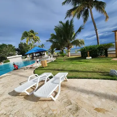 two white lounge chairs next to a swimming pool at Beachfront, Juandolio in Juan Dolio