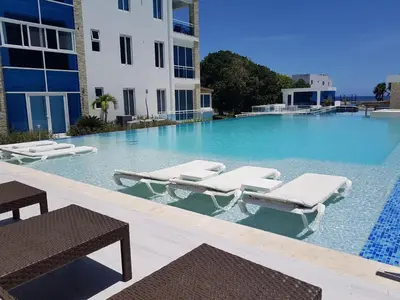a swimming pool with lounge chairs and a building at Koko and Suzy's ocean dream in Laguna del Higüero