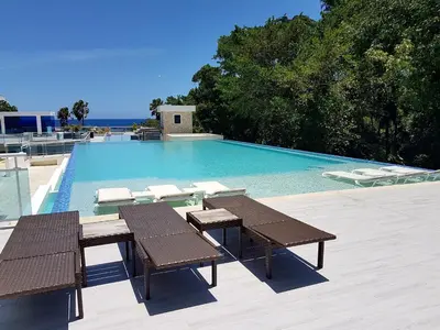 a swimming pool with two tables and chairs next to it at Koko and Suzy's ocean dream in Laguna del Higüero