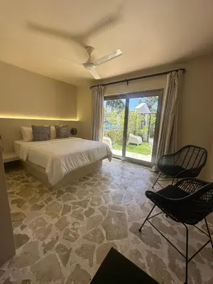 a bedroom with a bed and two chairs and a window at El Rincon de Abi in Las Terrenas