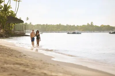 a man and a woman walking on the beach at Secrets La Romana All-Inclusive Adult Only Resort & Spa in Bayahibe