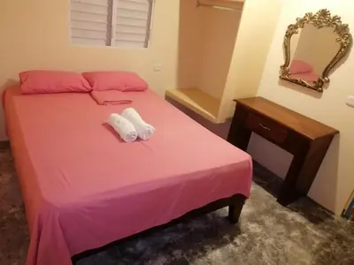 a bedroom with a pink bed with two towels on it at El Conde de Villa Rosa in Salado
