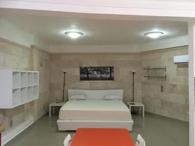 a bedroom with a white bed and two tables at Apartahotel Guaraguao in San Pedro de Macorís