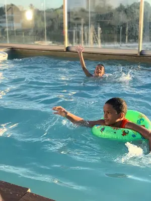 two children are swimming in a swimming pool at Mirador Colonial, en el Residencial Riviera Colonial in Santo Domingo