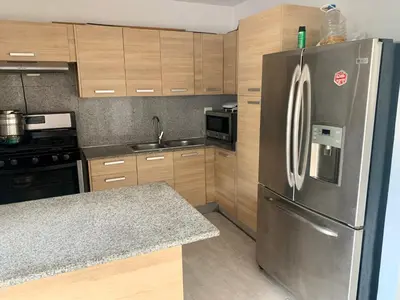 a kitchen with a stainless steel refrigerator and wooden cabinets at Mirador Colonial, en el Residencial Riviera Colonial in Santo Domingo