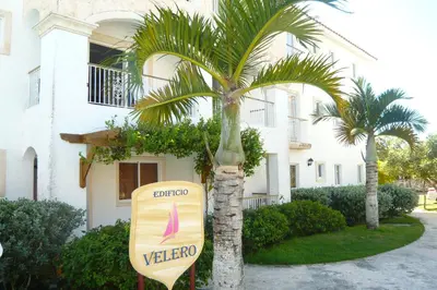 a sign in front of a building with a palm tree at Cadaques Caribe Boulevard Dominicus Americanus Carretera a Bayahibe Vel 206 in Bayahibe