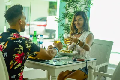 a man and a woman sitting at a table with a drink at Hotel Checkin El Cortecito Beach in Punta Cana
