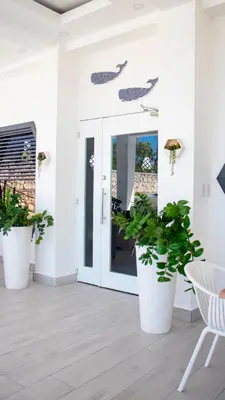 a porch with two large plants in large white pots at Hotel Capriccio Mare y Restaurante in Punta Cana
