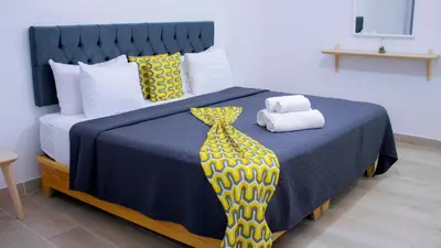 a bedroom with a bed with a blue comforter and a yellow tie at Hotel Capriccio Mare y Restaurante in Punta Cana