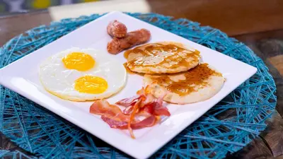 a plate of breakfast food with eggs bacon and sausage at Hotel Capriccio Mare y Restaurante in Punta Cana