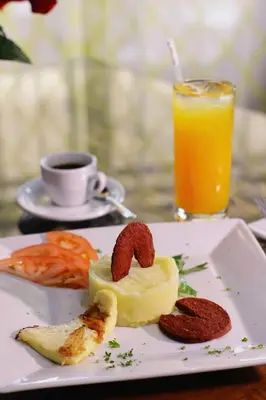 a plate of food and a glass of orange juice at Hotel Capriccio Mare y Restaurante in Punta Cana