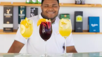 a man behind three wine glasses with fruit in them at Hotel Capriccio Mare y Restaurante in Punta Cana