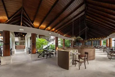 a restaurant with wooden ceilings and tables and chairs at Wyndham Alltra Punta Cana All Inclusive Resort in Punta Cana