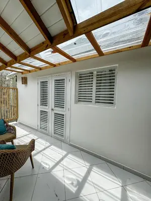 a living room with two windows and a chair at El Mosquito Boutique Hotel Playa Bonita in Las Terrenas