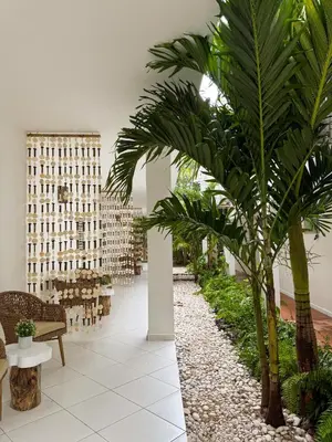 a lobby with palm trees and tables and chairs at El Mosquito Boutique Hotel Playa Bonita in Las Terrenas