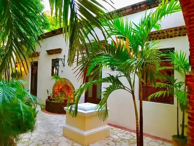a courtyard with palm trees in front of a house at Paseo Colonial - El Monasterio #4 in Santo Domingo