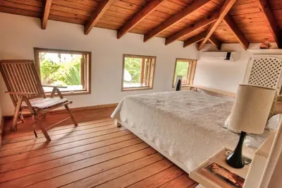 a bedroom with a bed and a chair and windows at Villa Maxime in Las Galeras